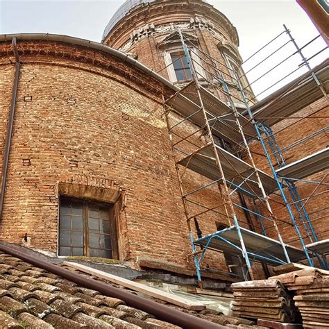 Esempio di restauro conservativo di un casale marchigiano con mattoni a vista e scala esterna.