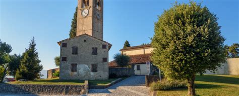 Veduta panoramica esterna della Pieve di San Pietro di Feletto inserita nel contesto collinare.