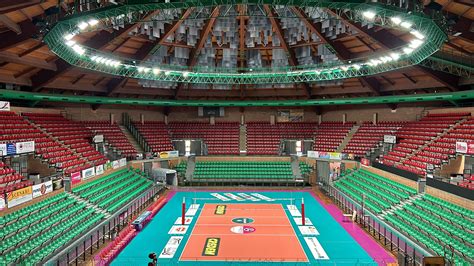 Assemblea pubblica o dibattito civico in un palazzetto dello sport, con persone che ascoltano un oratore