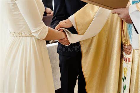 Sacerdote che tiene un'omelia in una chiesa durante un matrimonio, con sposi e invitati che ascoltano attentamente