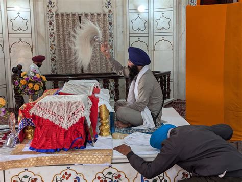 Sikh che pregano in gruppo durante un Ardas, possibilmente in un ambiente domestico o gurdwara.