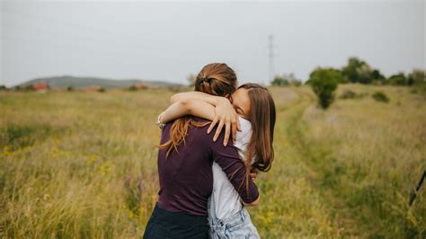 Foto di un abbraccio tra due donne, una delle quali indossa abiti civili e l'altra abiti più tradizionali, a simboleggiare l'incontro di percorsi di vita diversi.