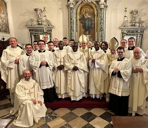 gruppo di nuovi sacerdoti in processione durante un'ordinazione, sorridenti e gioiosi