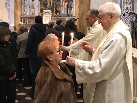 Sacerdote che impartisce la benedizione della gola con candele incrociate