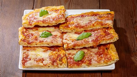 Foto di una pizza in teglia servita su un tagliere di legno