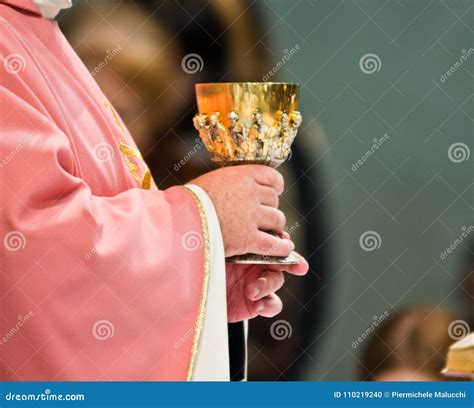 Mani di sacerdote che innalzano il calice durante la Consacrazione