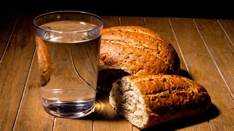 Immagine stilizzata di pane e acqua su un tavolo rustico, simbolo del digiuno.