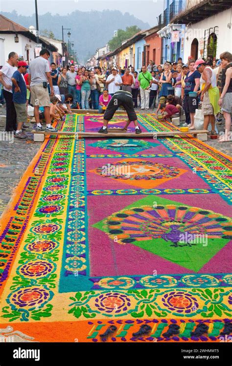 Foto dettagliata di un tappeto artistico realizzato in segatura colorata raffigurante un tema religioso.