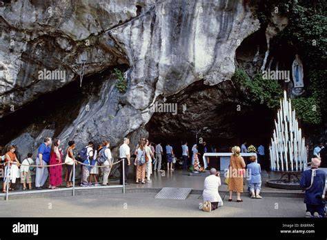 Pellegrini in preghiera e persone malate in sedia a rotelle alla Grotta di Massabielle a Lourdes