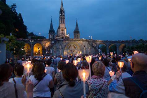 Processione serale con fiaccole a Lourdes, con migliaia di pellegrini che pregano