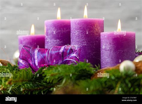 Una corona d'Avvento con quattro candele, tre viola e una rosa, disposta su uno sfondo verde.