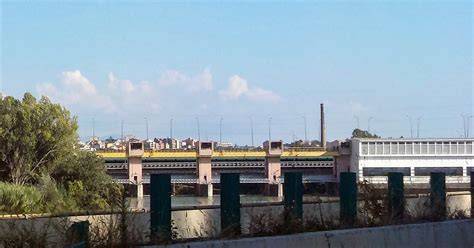 Vista aerea o frontale della diga di Castel Giubileo e del viadotto del Grande Raccordo Anulare che lo sovrasta, con i resti del vecchio ponte in ferro