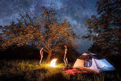 Ragazzi in attività di gruppo all'aperto, accampamento notturno con fuoco