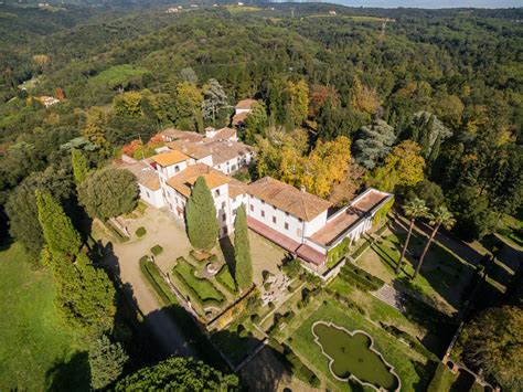 Foto panoramica della villa rinascimentale circondata da boschi e ulivi, con vista sulla città di Lucca in lontananza