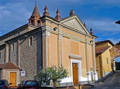 Foto della facciata della chiesa di Qualso con l'atrio settecentesco e i cipressi