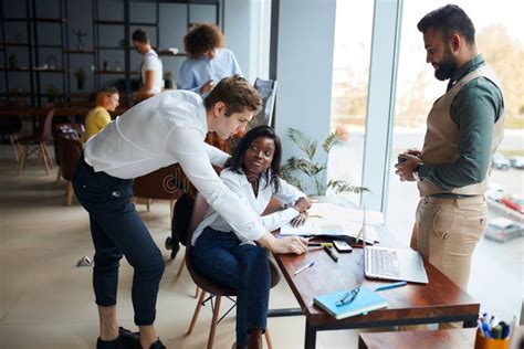 Ragazzi che lavorano insieme in una redazione giornalistica, sorridenti e impegnati.