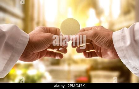 Mani di un sacerdote che benedice oggetti religiosi, come un rosario e una medaglietta, con acqua santa.