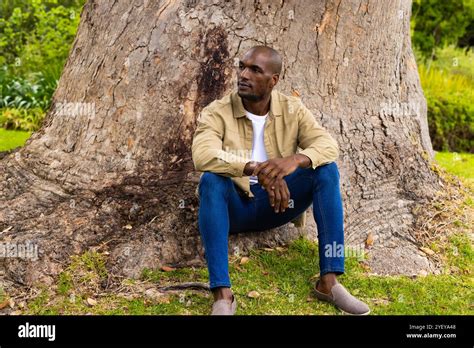 Thematic photo of an old man sitting under a tree, with a priest approaching him