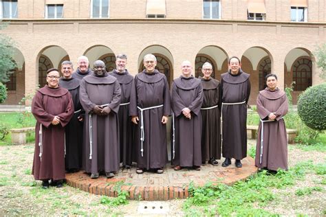 Foto di gruppo di frati francescani conventuali a Lourdes, sorridenti e accoglienti