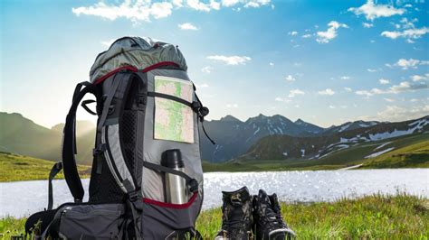 Composizione di attrezzatura da trekking e pellegrinaggio su fondo bianco, con zaino, scarpe, borraccia e altri accessori