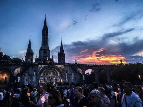Foto dei fedeli in preghiera durante una processione notturna a Lourdes