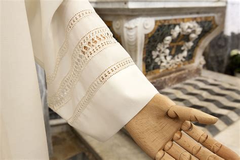 Dettaglio di un camice sacerdotale bianco con ricami in pizzo e collo romano