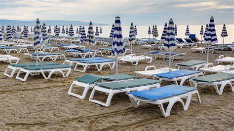 Stabilimento balneare elegante con lettini e ombrelloni color avorio sulla spiaggia