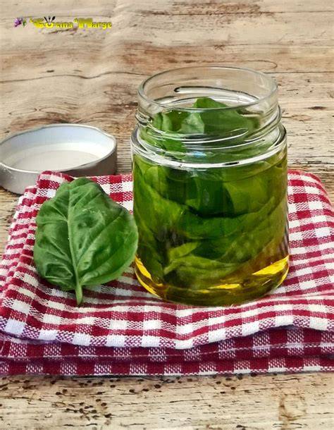 Olio al basilico fresco in bottiglia di vetro e foglie di basilico