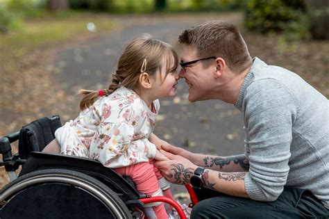 Foto di famiglia che ride e si abbraccia, con un membro disabile
