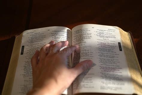 Una mano che tiene aperta una Bibbia, con una luce soffusa che illumina le pagine