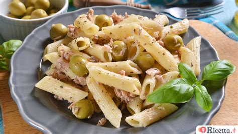 Foto di un piatto di pasta con tonno, olive nere e verdi, e foglie di basilico fresco