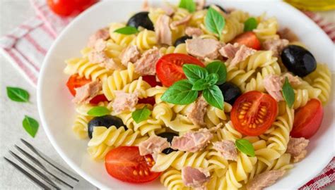 Foto di un'insalata di pasta fredda estiva con tonno, olive e basilico in una ciotola