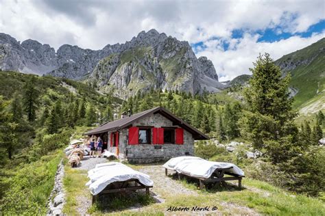 Foto panoramica del Rifugio San Fermo con la chiesetta adiacente e le montagne circostanti