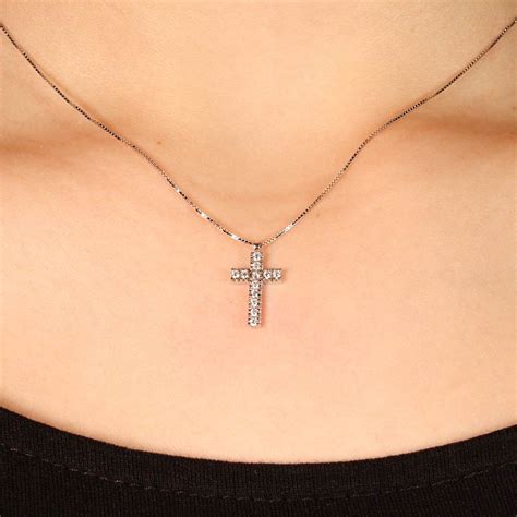 Fotografia: Dettaglio di una collana con croce moderna indossata, che mostra la versatilità dello stile