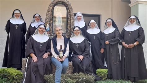 Monaca di clausura seduta, con un libro in mano, in una cella semplice e luminosa