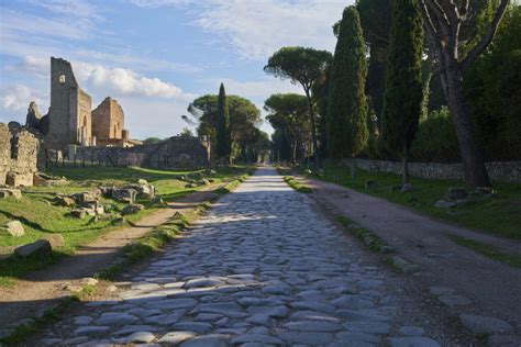 Veduta del basolato romano originale dell'Appia Antica con monumenti funerari e cipressi