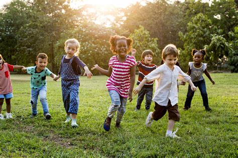 Foto di bambini che giocano insieme in un ambiente estivo, con simboli di inclusione