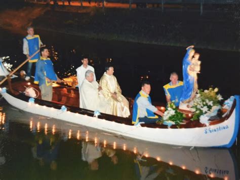 Foto panoramica della processione della Madonna in Barca sul Fiumazzo, Campagna Lupia, con fedeli a terra e barche illuminate