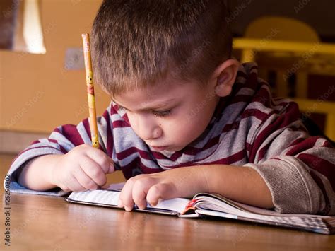 Bambino che legge e scrive con attenzione, circondato da lettere M e N illustrate