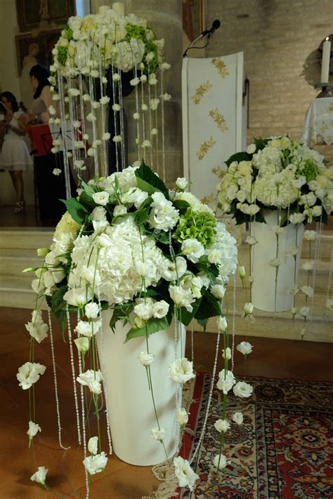 Eleganti alzate per fiori con composizioni floreali posizionate sull'altare o nelle vicinanze, in una chiesa