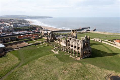 Foto panoramica delle rovine dell'Abbazia di Whitby sulla scogliera con il mare agitato sullo sfondo, atmosfera drammatica