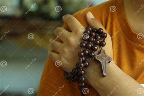 mano che tiene un rosario con luce che simboleggia la fede