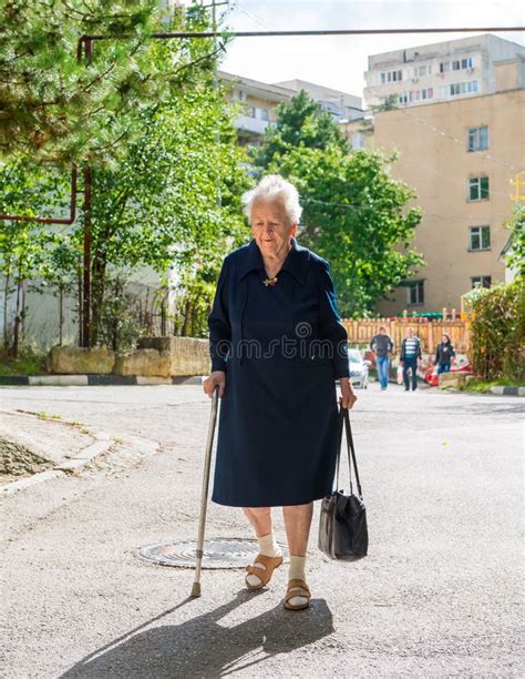 Una donna anziana che cammina con l'ausilio di un deambulatore in un giardino