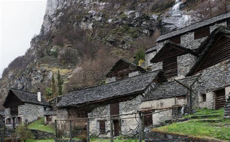 Veduta di un villaggio alpino con case antiche, sotto un cielo plumbeo