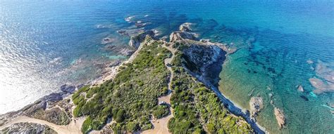 Veduta panoramica dell'Agriturismo Il Mirto immerso nella campagna della Nurra con gli alloggi in primo piano e la macchia mediterranea sullo sfondo