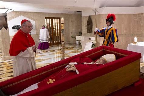 Papa Francesco mentre bussa alle ante di bronzo della chiesa del Padre Nostro nel carcere di Rebibbia, circondato da fiori e fedeli
