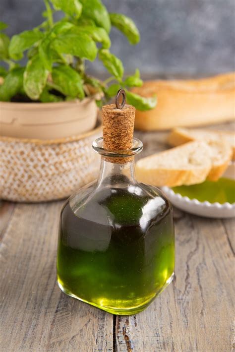 Bottiglia di olio extravergine aromatizzato al basilico con foglie di basilico fresche e pomodori