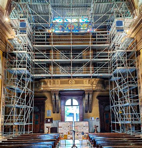 Chiesa antica in fase di restauro, con impalcature esterne e operai al lavoro per la conservazione del patrimonio.
