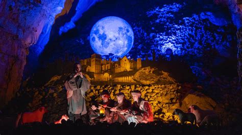 Foto di un presepe vivente all'interno delle Grotte di Postumia, con personaggi in costume e illuminazione suggestiva