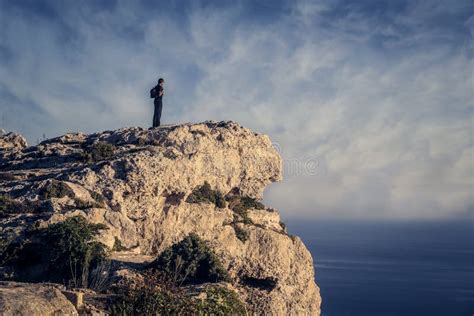 fotografia di una persona in piedi su una montagna, che guarda l'orizzonte, simboleggiando forza e coraggio